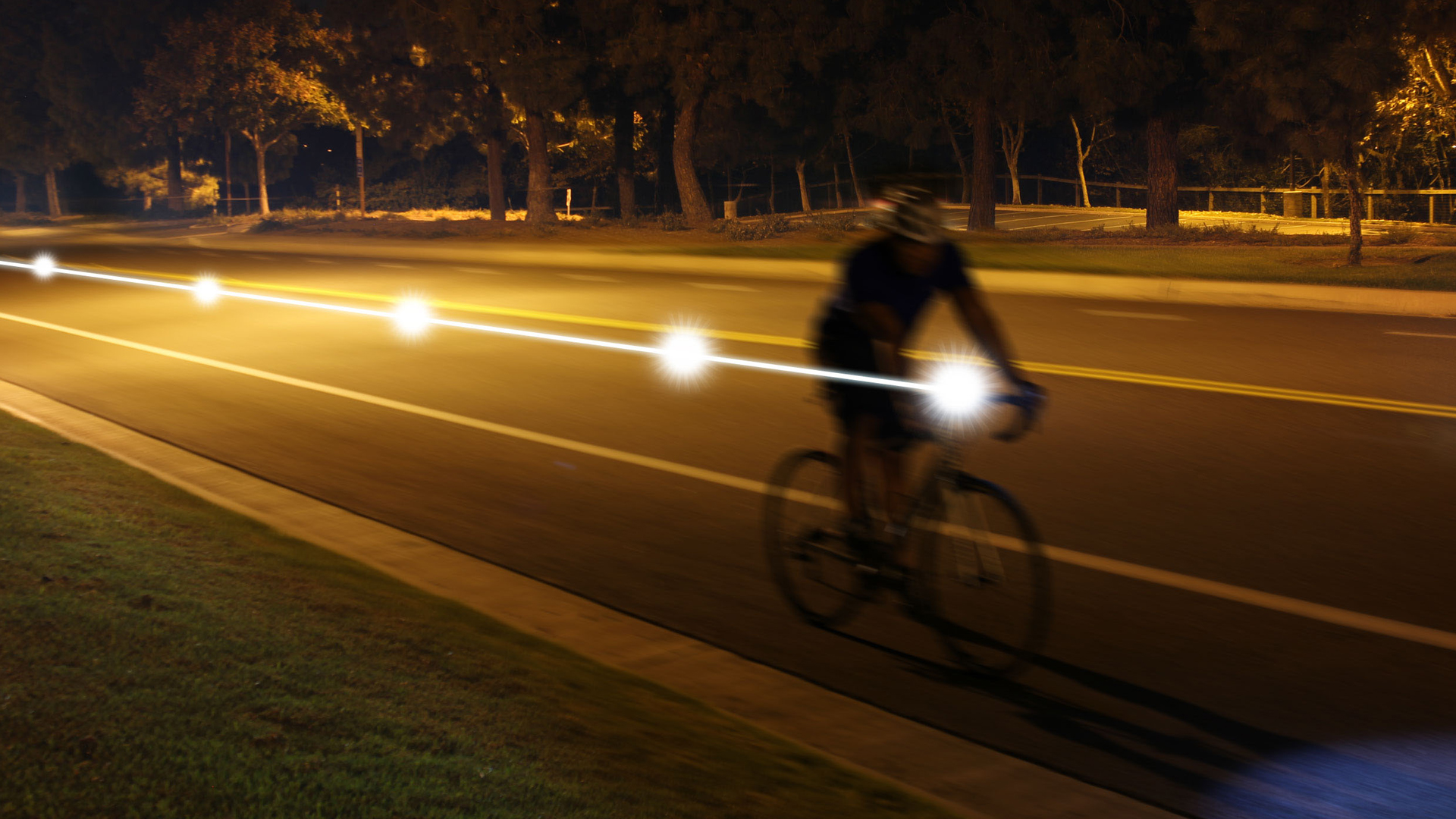 Cyclist riding at night with a bright headlight beam illuminating the road